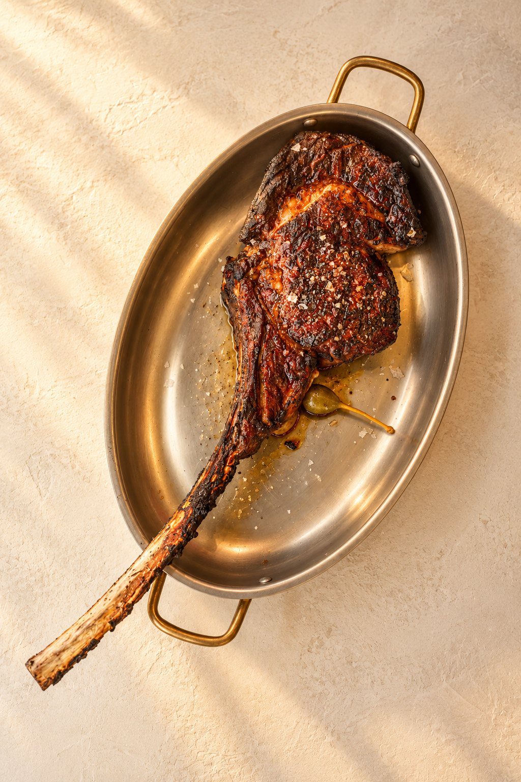 Tomahawk steak in a brass-handled pan